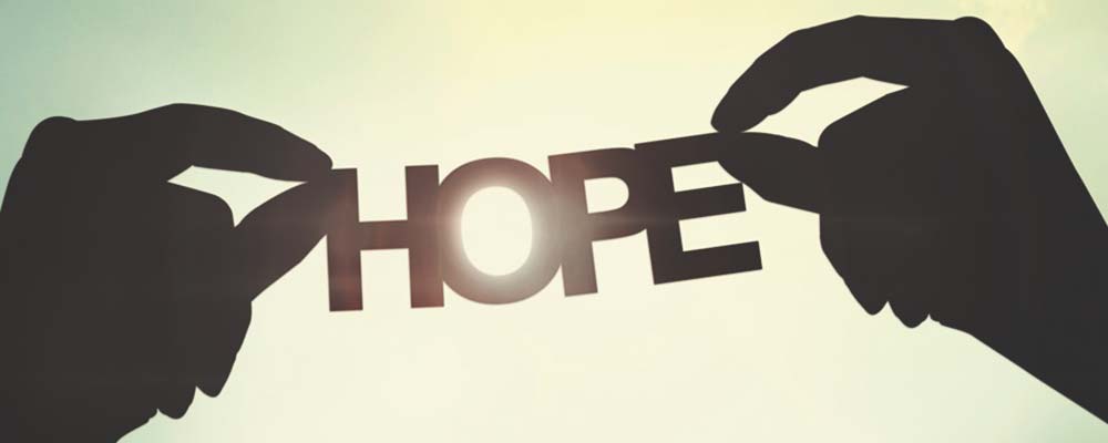 silhouette of two hands holding up the word "hope"
